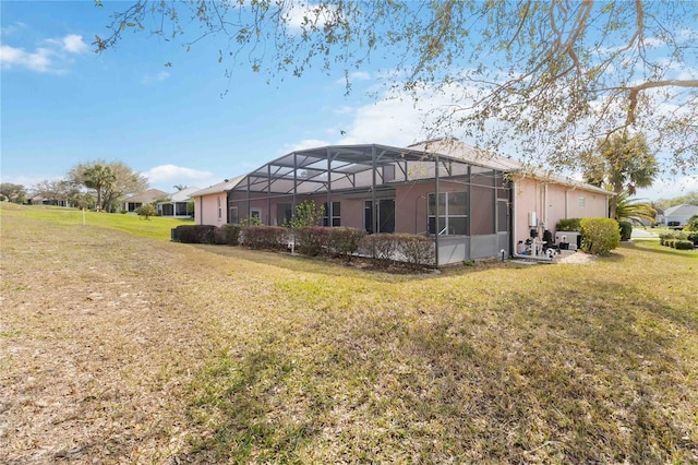 back of property featuring glass enclosure and a lawn