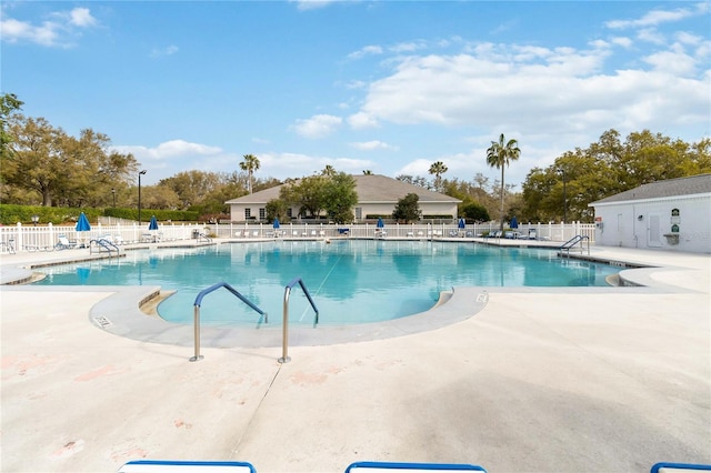 community pool with a patio area and fence