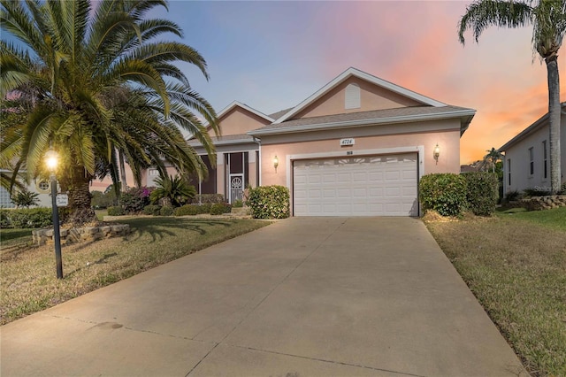 single story home with stucco siding, an attached garage, concrete driveway, and a yard