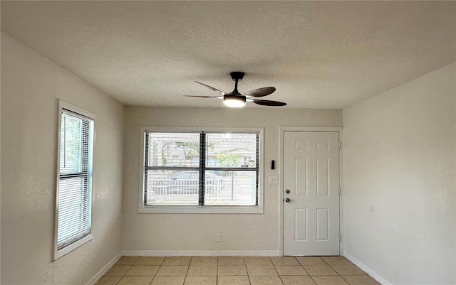 entryway featuring light tile patterned flooring, baseboards, a textured ceiling, and a ceiling fan