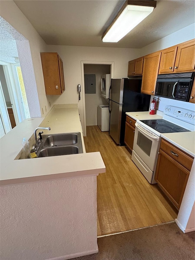 kitchen with a sink, light countertops, black microwave, and white range with electric stovetop