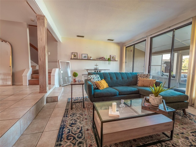 living area featuring stairway, light tile patterned floors, visible vents, and ornate columns