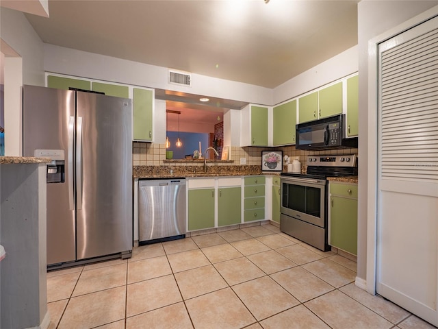 kitchen featuring a sink, backsplash, appliances with stainless steel finishes, green cabinetry, and light tile patterned floors