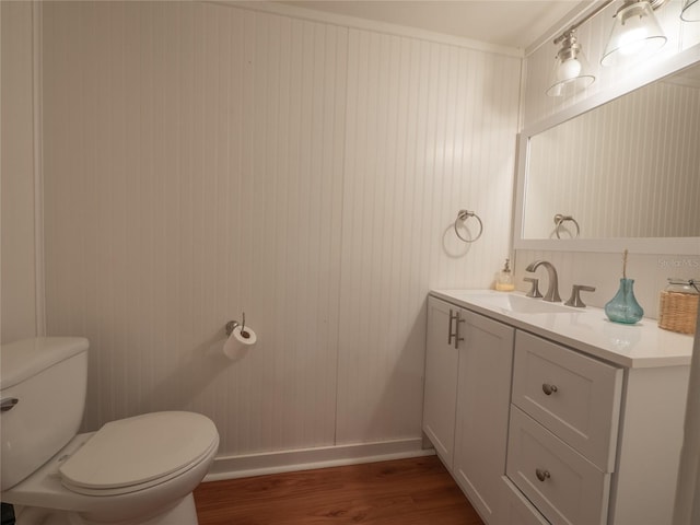 bathroom with vanity, toilet, wood finished floors, and baseboards