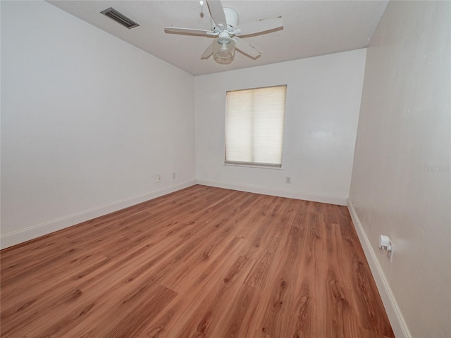 unfurnished room with visible vents, light wood-style flooring, a ceiling fan, and baseboards