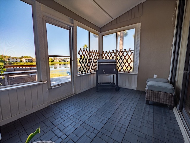 sunroom / solarium with plenty of natural light, lofted ceiling, and a water view