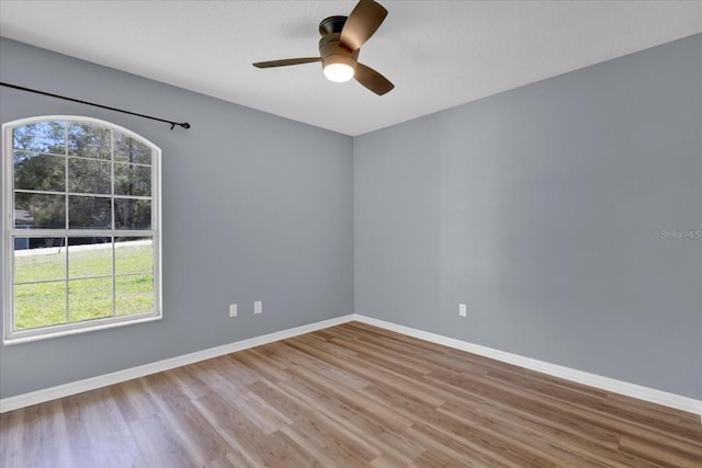 spare room with ceiling fan, baseboards, and wood finished floors