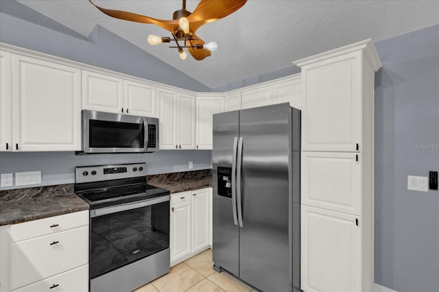 kitchen with lofted ceiling, dark countertops, appliances with stainless steel finishes, and white cabinetry