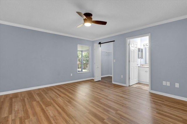 unfurnished bedroom featuring light wood-style flooring, a ceiling fan, ornamental molding, connected bathroom, and baseboards