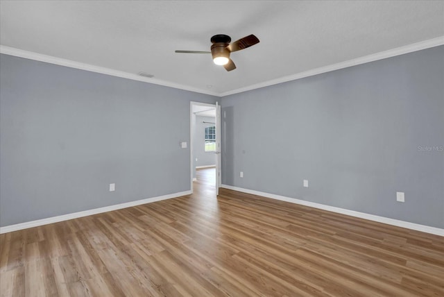 spare room featuring light wood-type flooring, visible vents, crown molding, baseboards, and ceiling fan