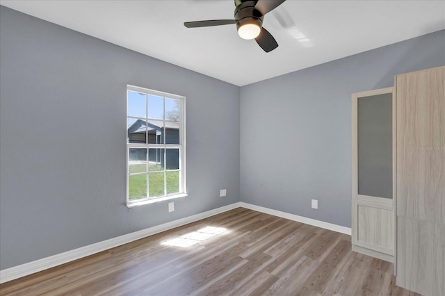 unfurnished room with a ceiling fan, wood finished floors, and baseboards