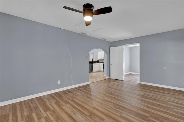 empty room featuring a ceiling fan, visible vents, baseboards, light wood-style flooring, and arched walkways