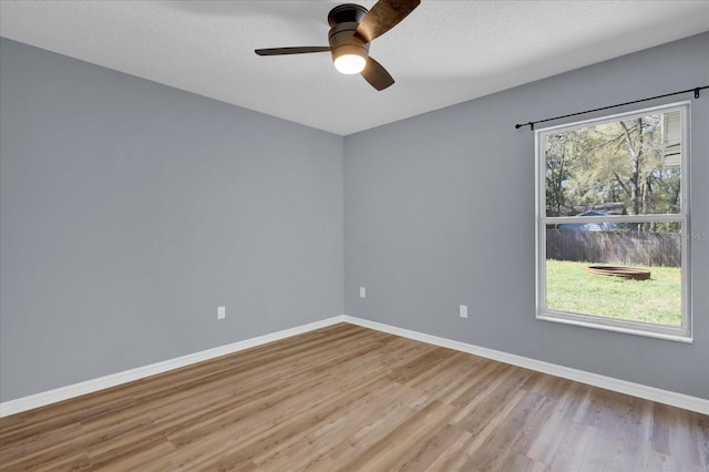 spare room with a textured ceiling, a ceiling fan, baseboards, and wood finished floors