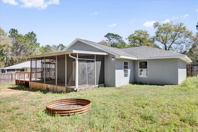 back of house featuring stucco siding, fence, a yard, and a sunroom