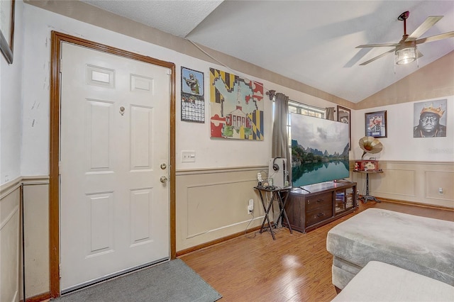 foyer entrance with lofted ceiling, wood finished floors, and wainscoting