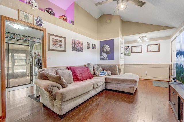 living area with high vaulted ceiling, ceiling fan, wainscoting, and hardwood / wood-style flooring