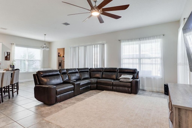 living room with visible vents, light tile patterned floors, ceiling fan with notable chandelier, and baseboards