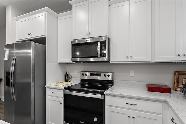 kitchen featuring light stone counters, appliances with stainless steel finishes, and white cabinets