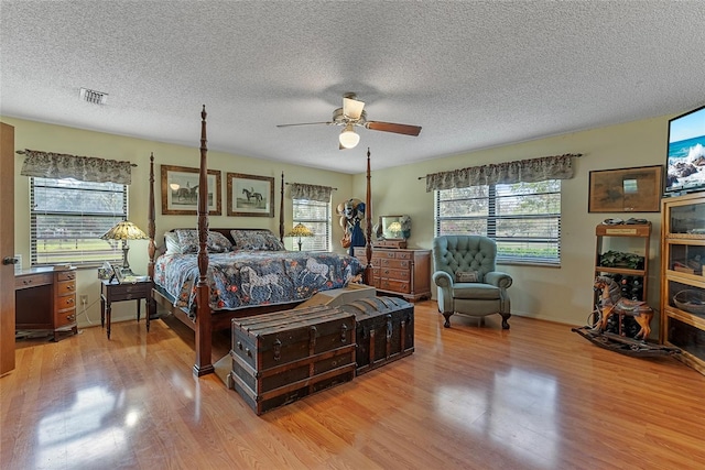 bedroom featuring visible vents, a textured ceiling, a ceiling fan, and wood finished floors