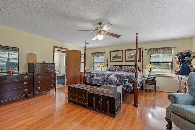 bedroom featuring multiple windows, a textured ceiling, a ceiling fan, and light wood finished floors