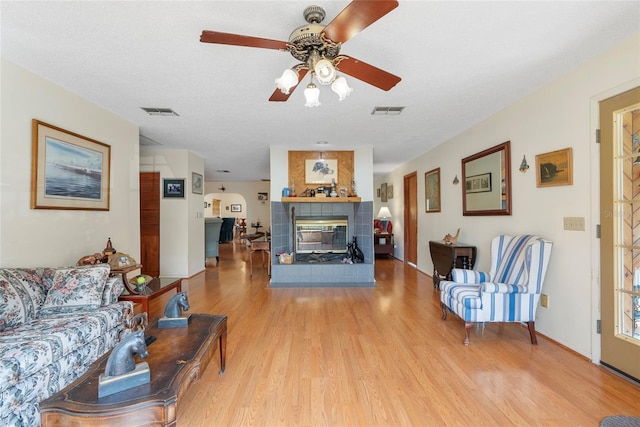 living room with visible vents, a ceiling fan, wood finished floors, and a fireplace