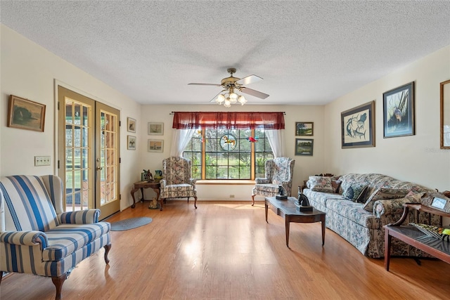 living room with a textured ceiling, wood finished floors, french doors, and ceiling fan