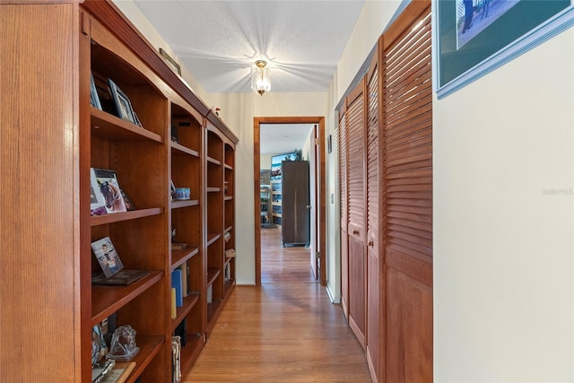 hall featuring a textured ceiling and light wood finished floors