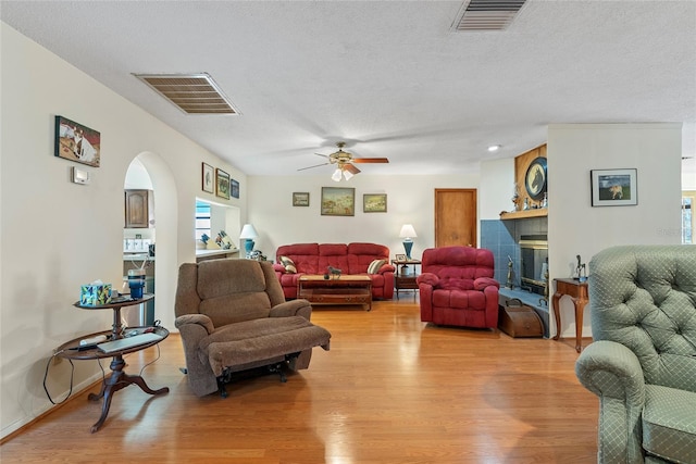 living room with arched walkways, visible vents, and light wood-type flooring