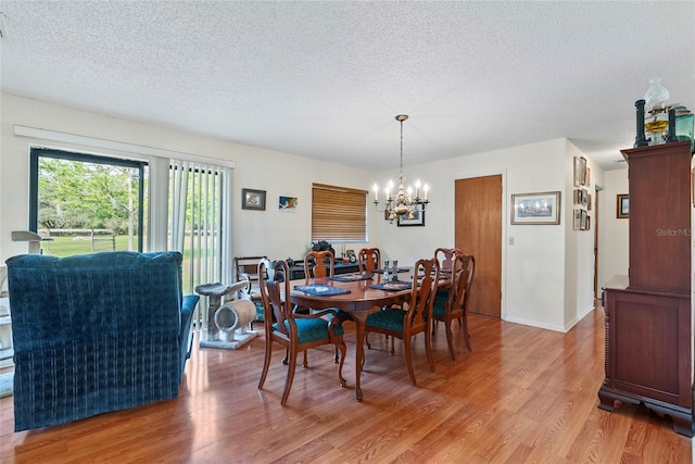 dining space with a textured ceiling, a chandelier, and light wood finished floors