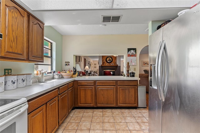 kitchen featuring visible vents, brown cabinets, stainless steel fridge with ice dispenser, light countertops, and light tile patterned floors