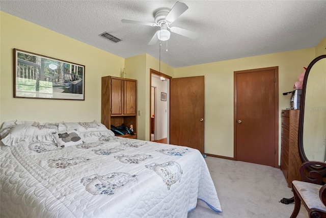 bedroom with visible vents, two closets, ceiling fan, light carpet, and a textured ceiling