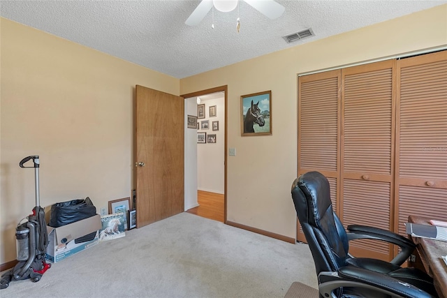 home office featuring carpet flooring, a ceiling fan, visible vents, and a textured ceiling