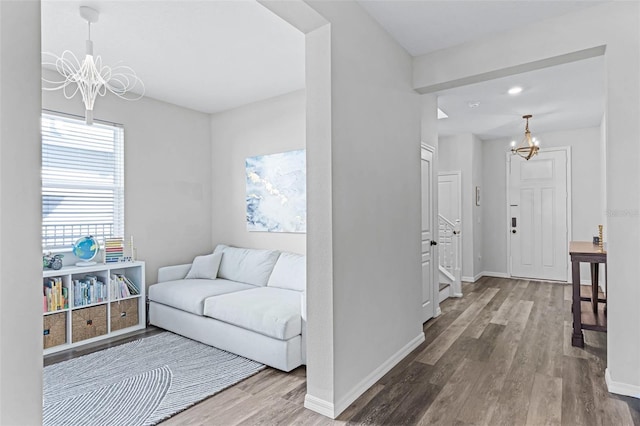 living room featuring baseboards, stairs, an inviting chandelier, and wood finished floors