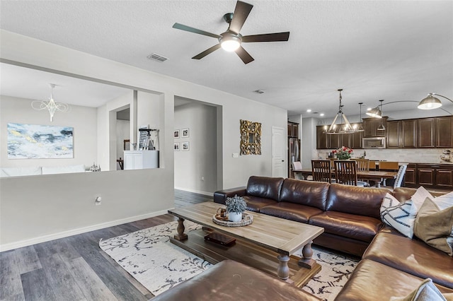 living area featuring dark wood-style floors, visible vents, a textured ceiling, and baseboards