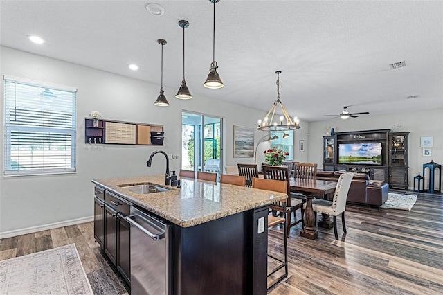 kitchen featuring dark wood-type flooring, pendant lighting, a kitchen island with sink, a sink, and open floor plan