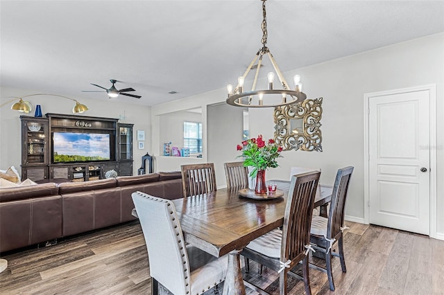 dining area with light wood-style flooring, ceiling fan with notable chandelier, and baseboards