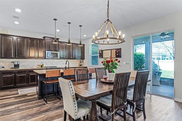 dining area featuring visible vents, plenty of natural light, an inviting chandelier, and light wood-style floors