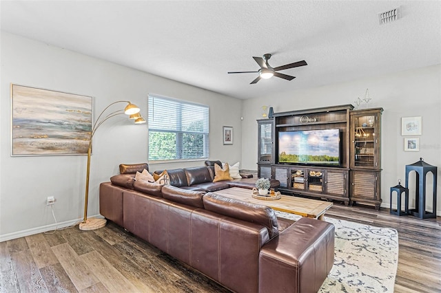 living area with visible vents, baseboards, wood finished floors, a textured ceiling, and a ceiling fan