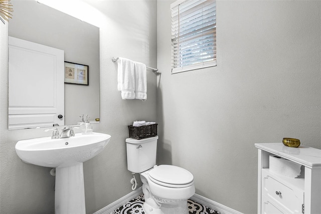 bathroom with toilet, baseboards, and a sink