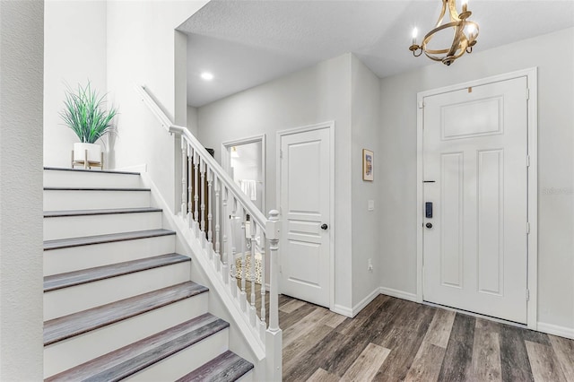 entrance foyer with stairway, baseboards, wood finished floors, and a chandelier