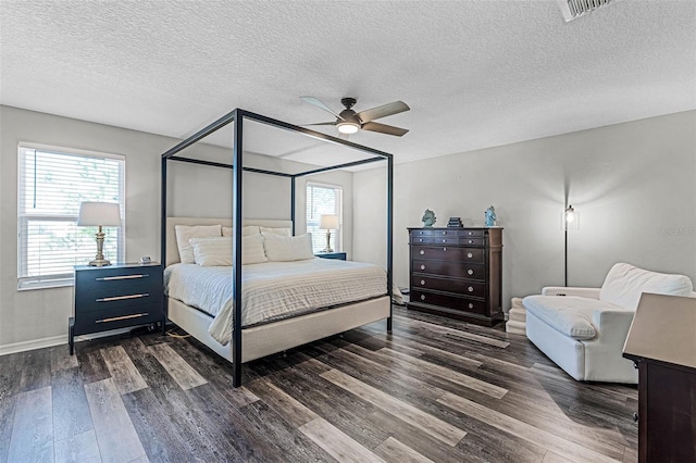 bedroom featuring visible vents, multiple windows, dark wood finished floors, and a ceiling fan