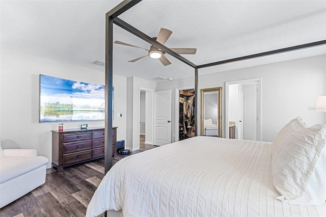 bedroom with a ceiling fan, wood finished floors, a spacious closet, a closet, and a textured ceiling