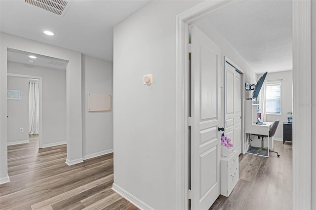 hall featuring visible vents, recessed lighting, baseboards, and wood finished floors