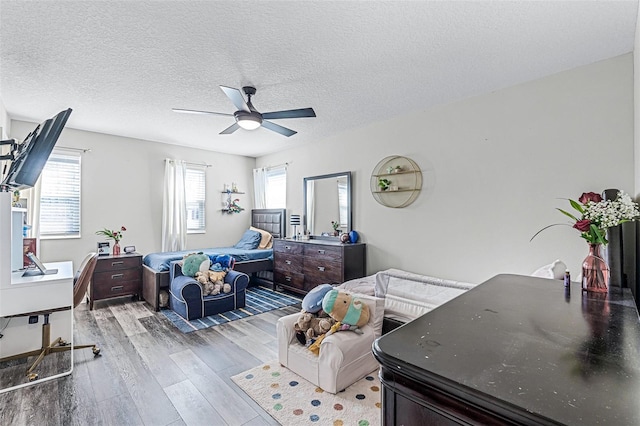 bedroom with ceiling fan, a textured ceiling, and wood finished floors