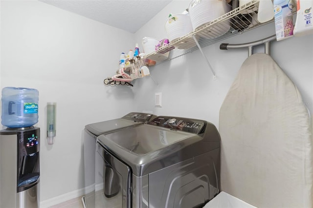 washroom with laundry area, separate washer and dryer, baseboards, and a textured ceiling