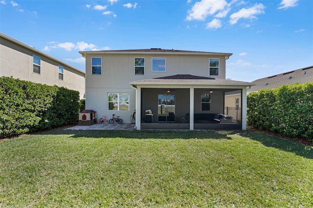 rear view of property featuring stucco siding, a sunroom, a lawn, and a patio area