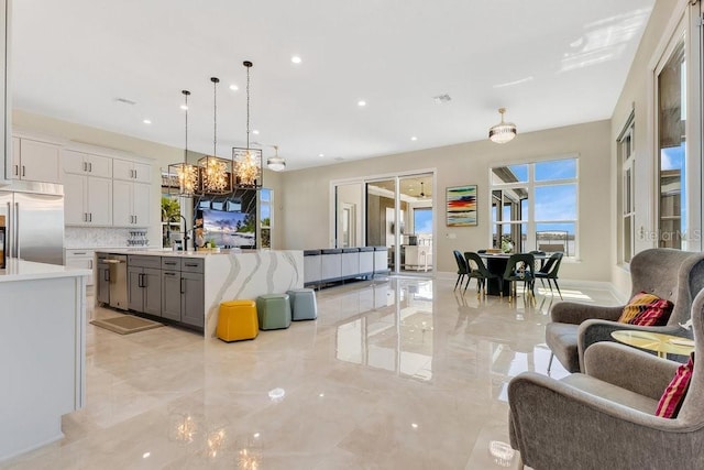 kitchen featuring marble finish floor, appliances with stainless steel finishes, open floor plan, and an inviting chandelier