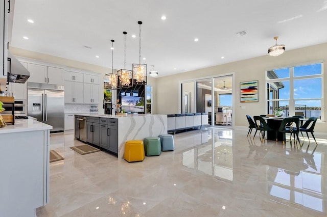 kitchen featuring stainless steel appliances, marble finish floor, and a healthy amount of sunlight