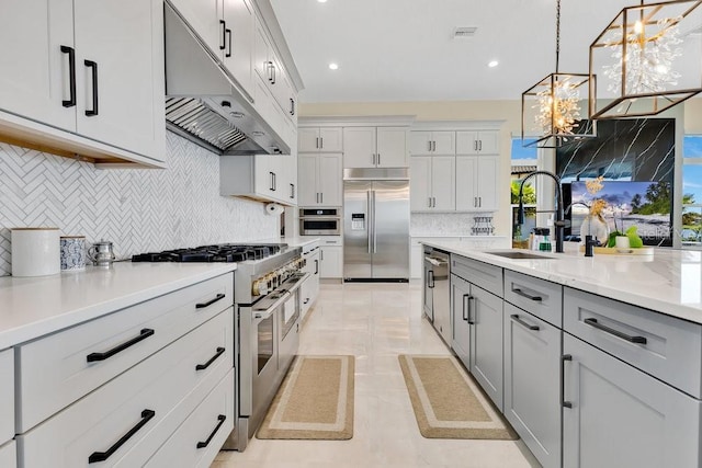 kitchen featuring an inviting chandelier, a sink, gray cabinetry, under cabinet range hood, and premium appliances