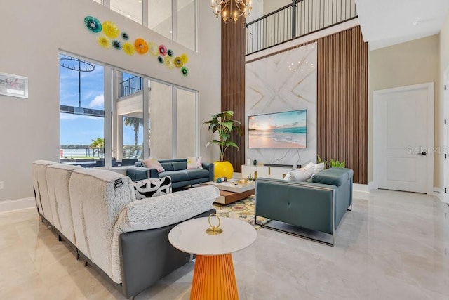 living area featuring a high ceiling, a notable chandelier, baseboards, and marble finish floor